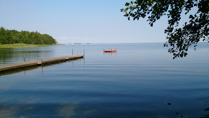 En lång brygga av trä sträcker sig i sjön och strax utanför ligger en flytbrygga.
